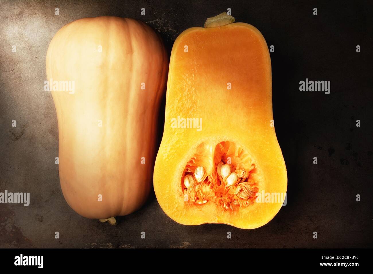 Butternut Squash cut in half showing both the inside and outside. Flat lay horizontal format with warm side light.. Stock Photo
