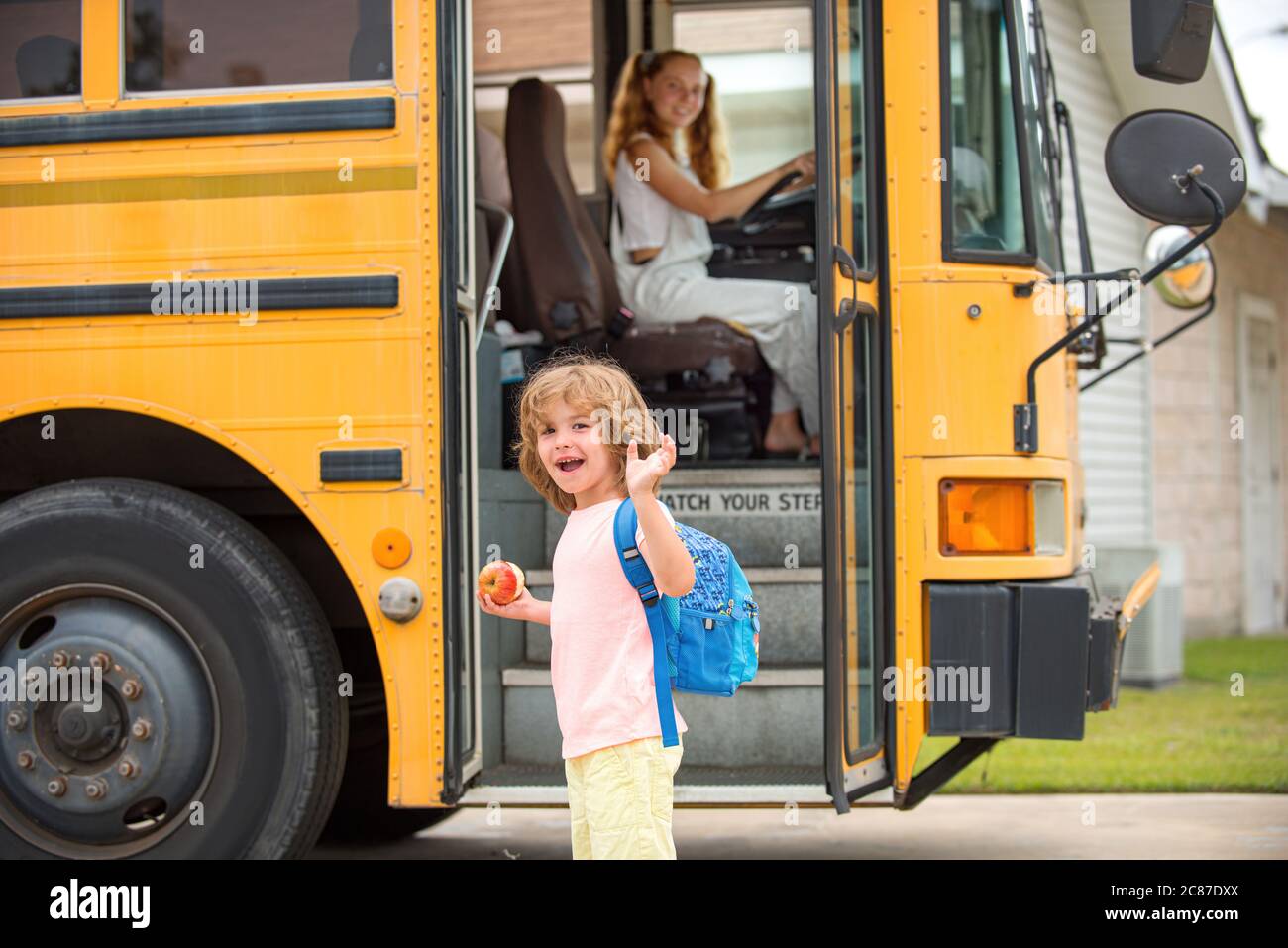 Child getting on school bus. Back to school and happy time. Little ready to study. Home education. Stock Photo