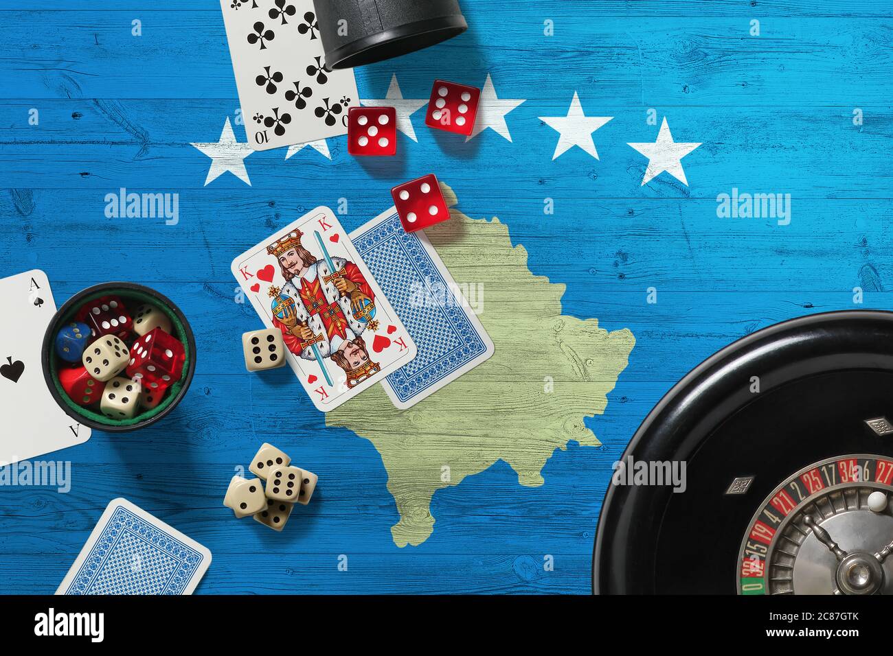 Kosovo casino theme. Aces in poker game, cards and chips on red table with national wooden flag background. Gambling and betting. Stock Photo