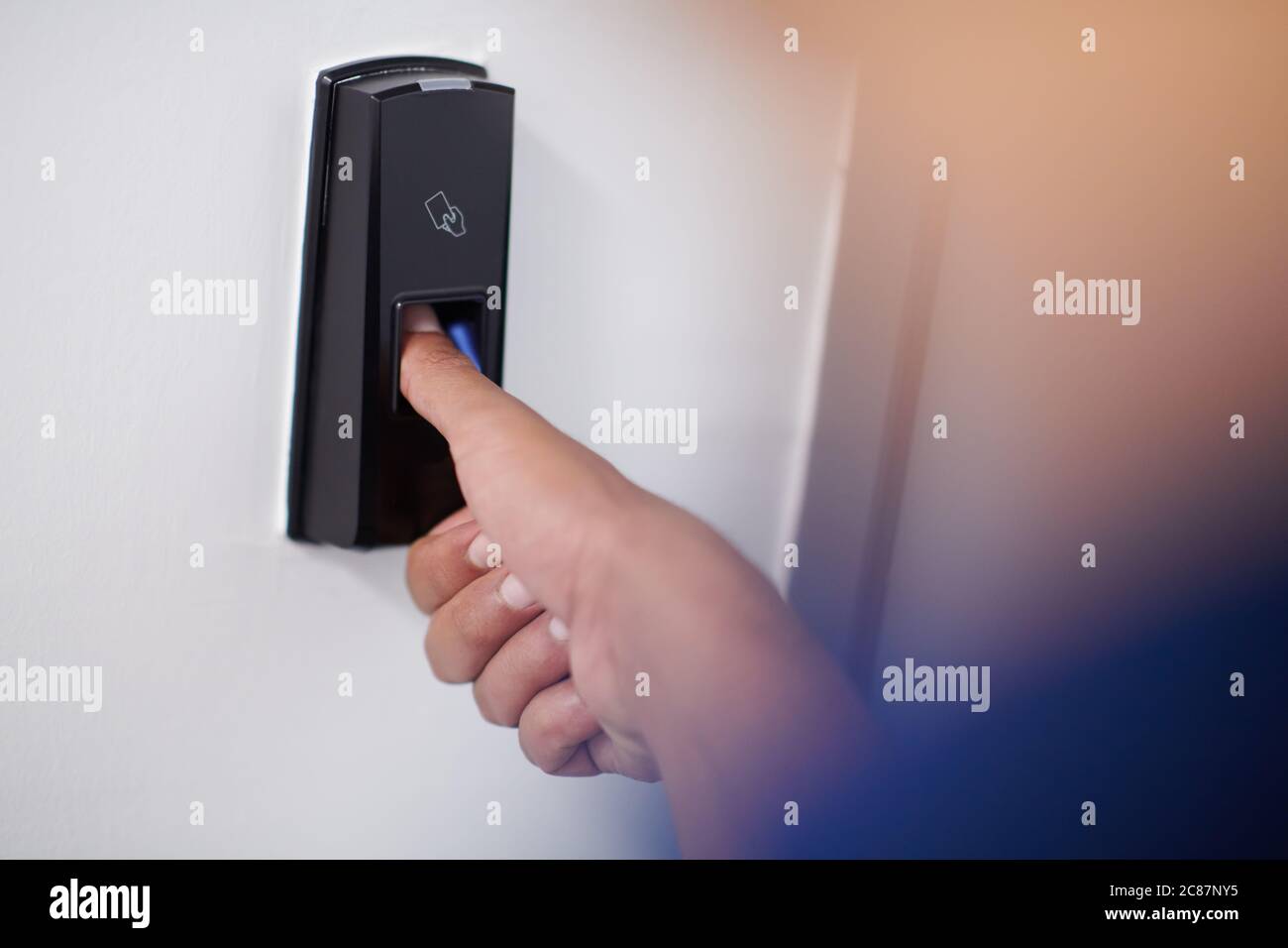 man pressing fingerprint scanner on alarm system indoors Finger print
