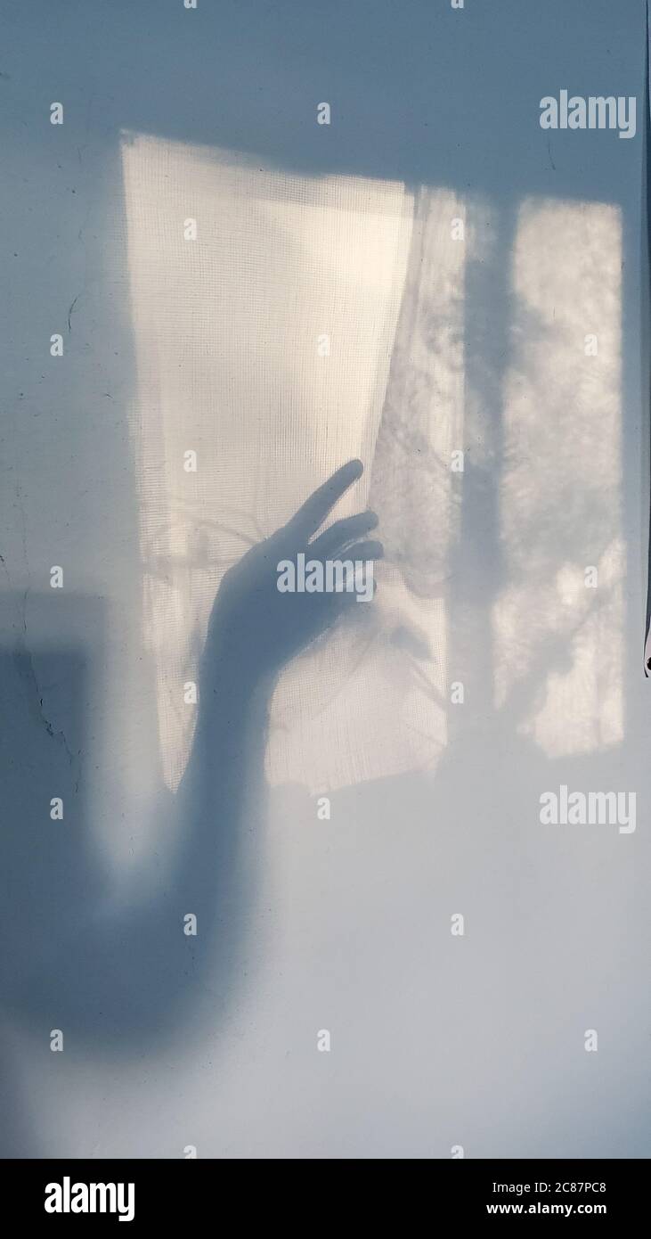 Blurry shadow of creepy hand silhouette looks like ghost out the window. Defocus palm of hand shadows on rough wall surface Stock Photo