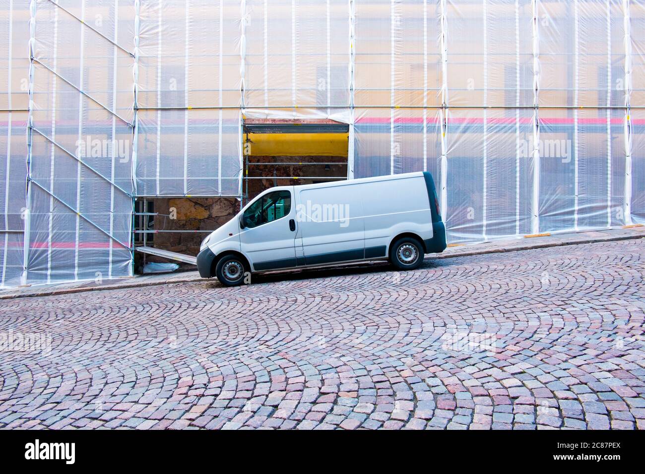 A cool, abstract, graphic look of a van parked in front of a building wrapped in construction fabric. In Helsinki, Finland. Stock Photo