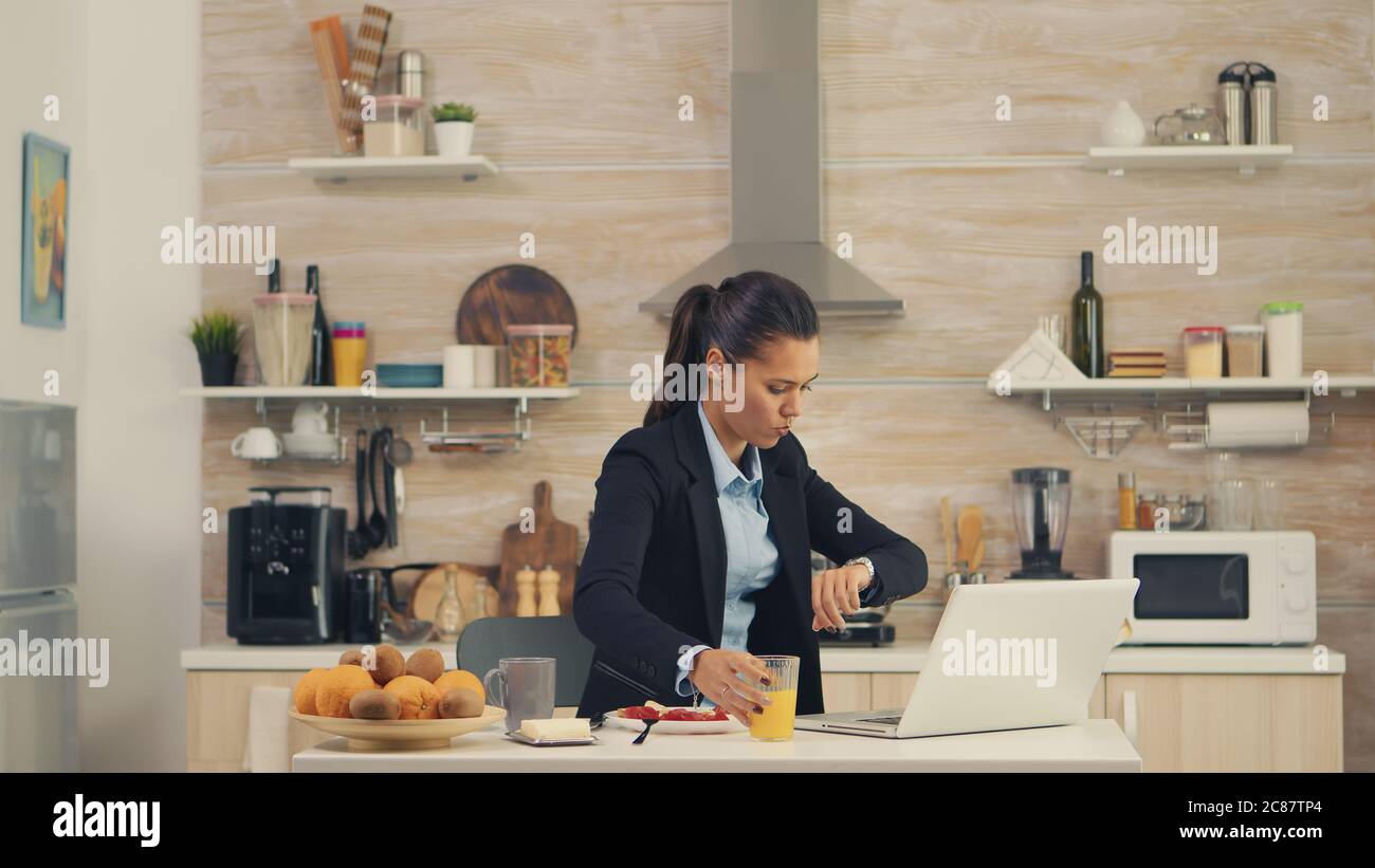 Freelancer woman late at the office while eating breakfast. Young freelancer working around the clock to meet her goals, stressful way of life, hurry, late for work, always on the run Stock Photo