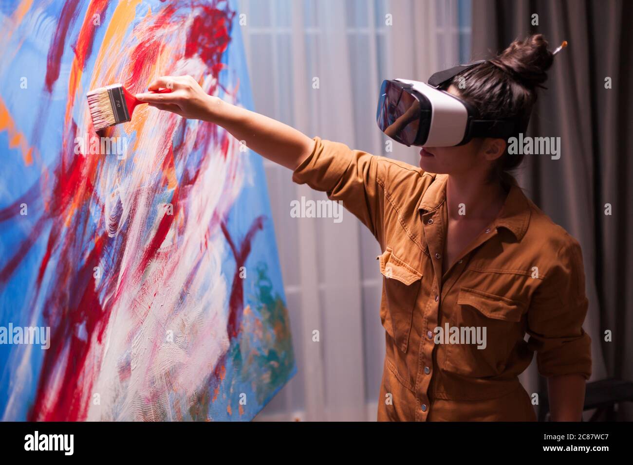 Creative painter with vr headset painting on canvas in art studio. Modern artwork paint on