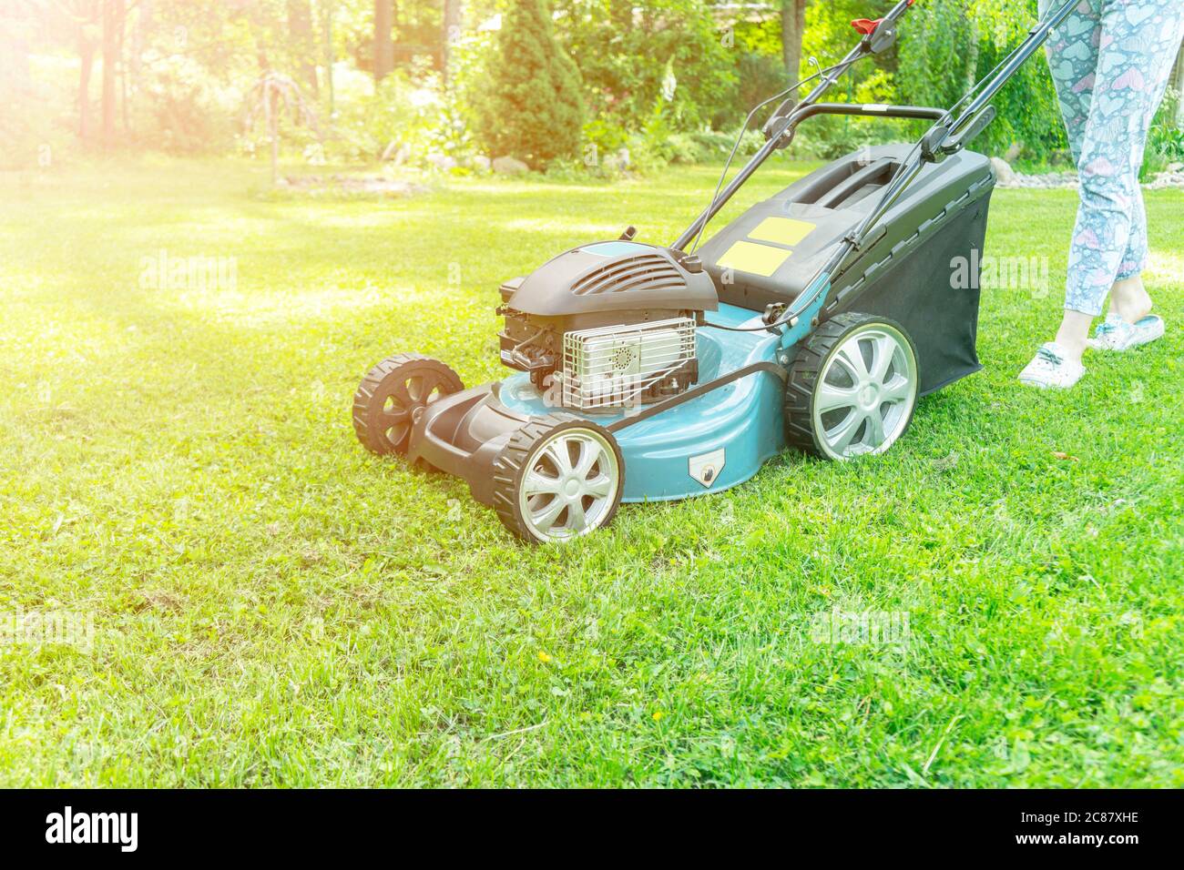 Beautiful girl cuts the lawn. Mowing lawns. Beautiful woman lawn mower