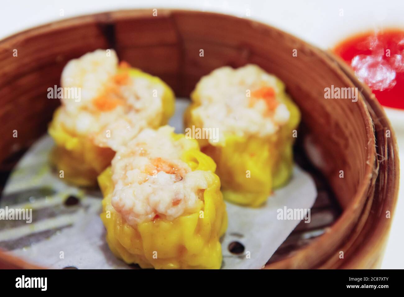 Fresh made Sui Mai placed in a hot bamboo steamer or basket presented on the table. A very popular dim sum dish for the Chinese people. Stock Photo