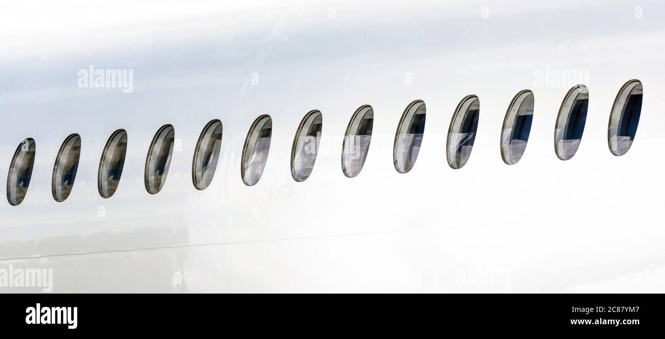 Many portholes in a row on the fuselage of a white airplane Stock Photo