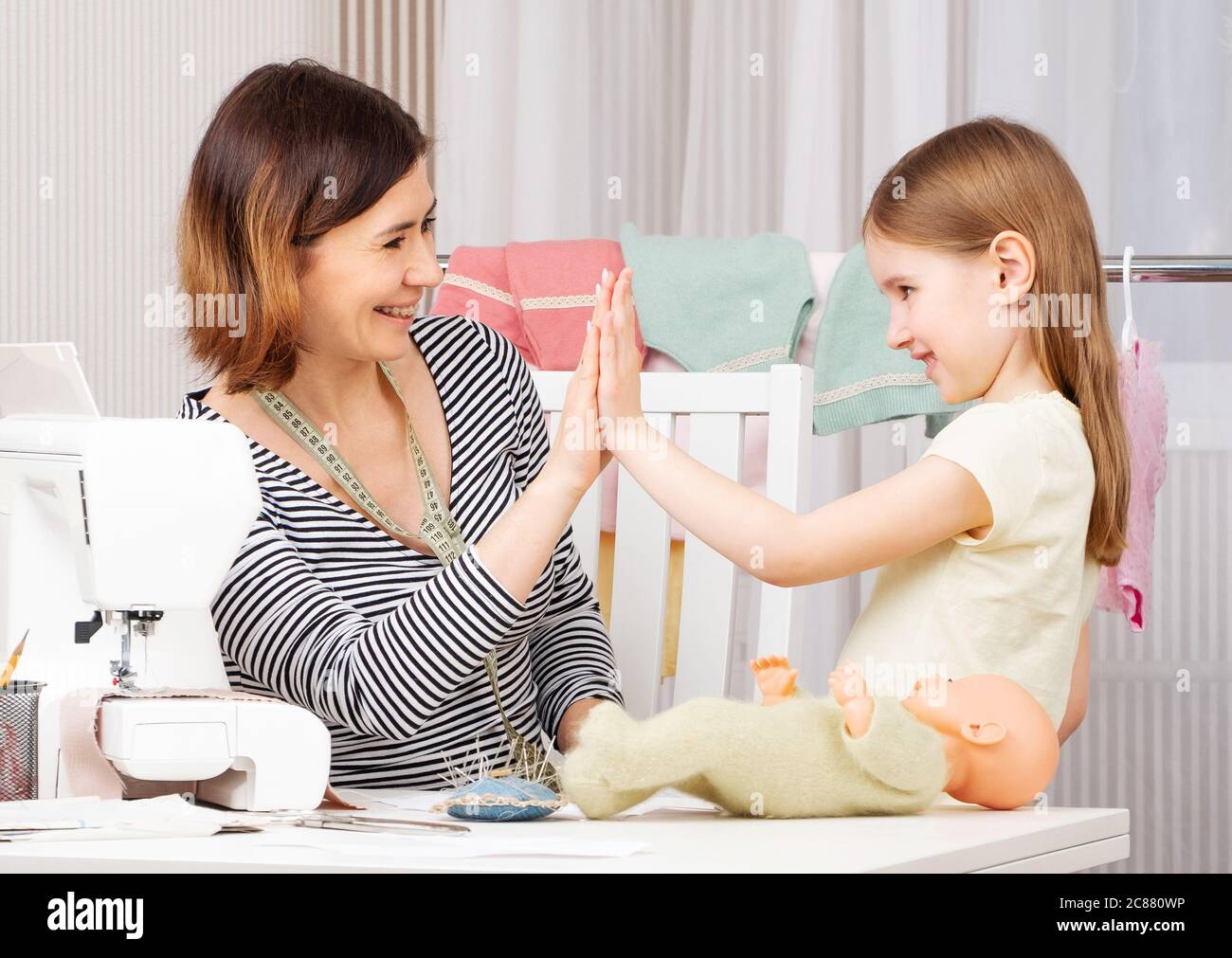 Smiling girl and woman making perfect and efficient sewing team Stock Photo