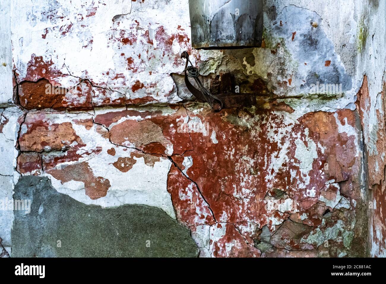 Decayed old white wall with red bricks and metal sewer, background Stock Photo