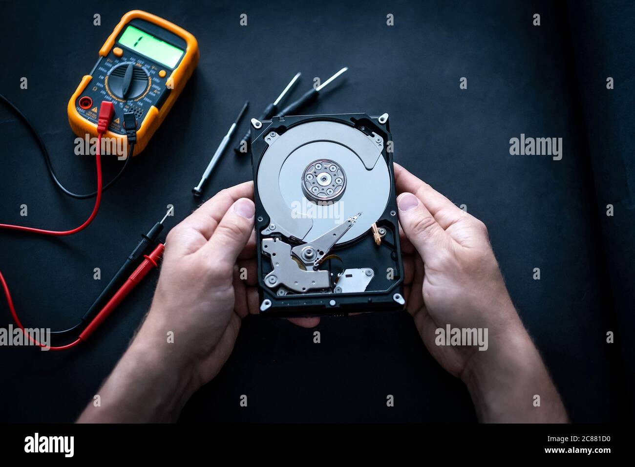 Man hands and digital mutimeter fixing hard drive Stock Photo