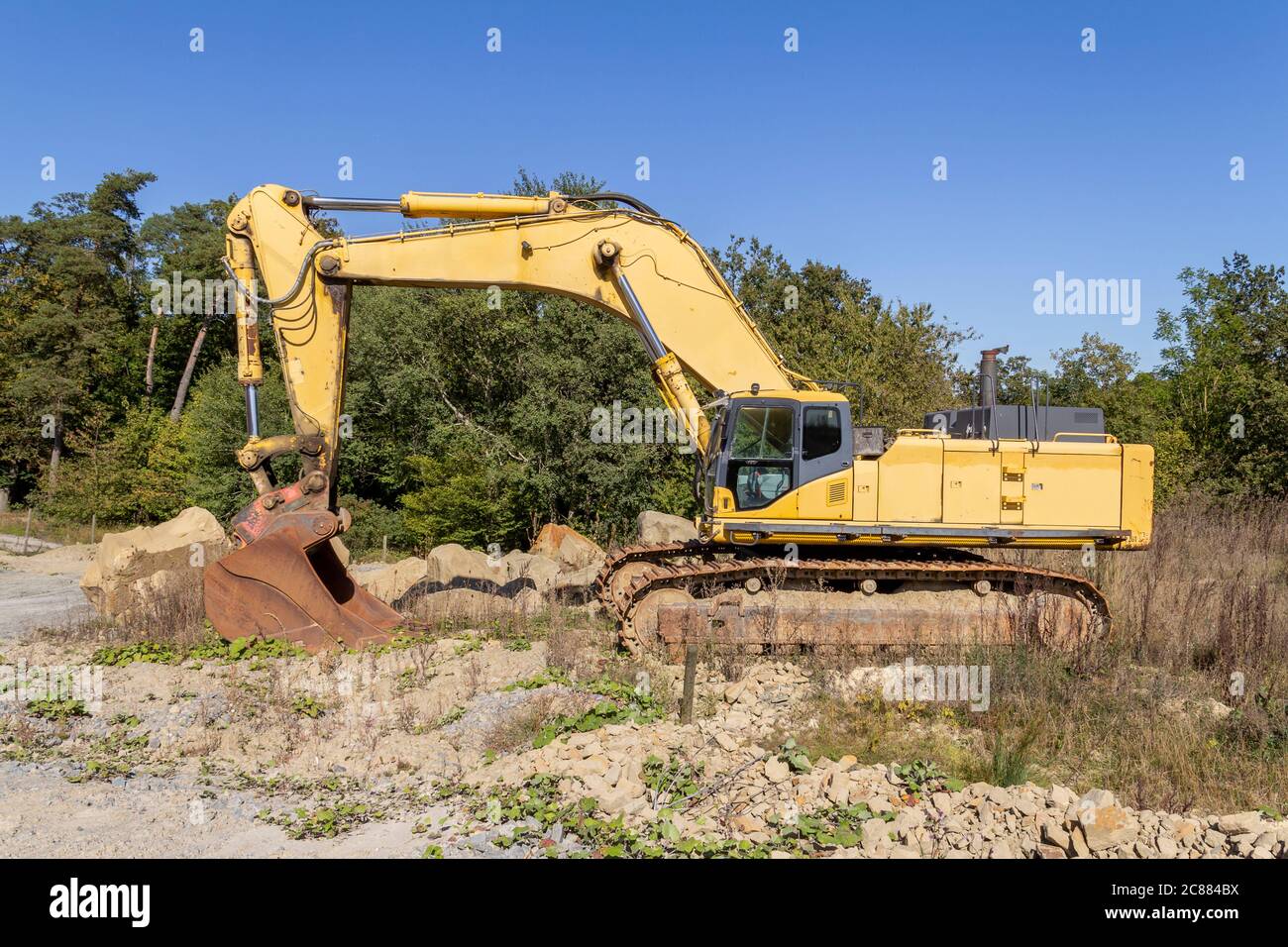 yellow excavator at a construction site in sunny ambiance Stock Photo ...