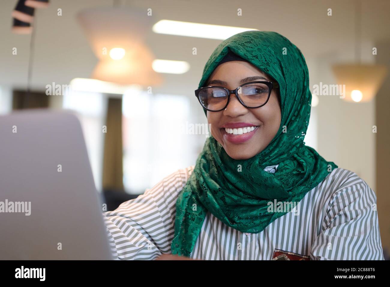 african muslim business woman wearing a green hijab while working on ...