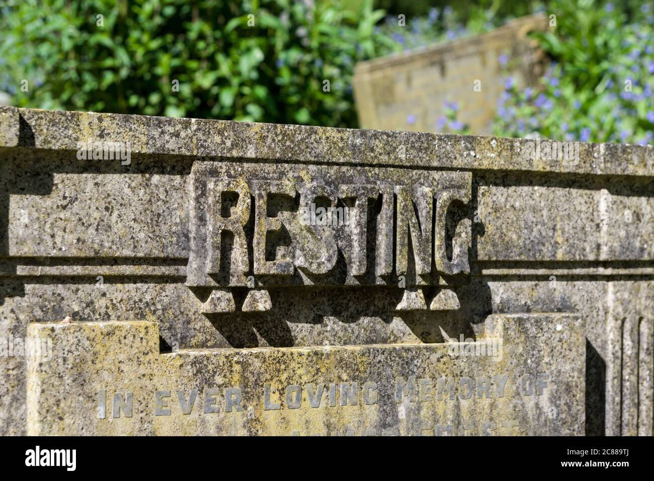 The word 'Resting' carved in stone on top of a gravestone in a UK country churchyard. Stock Photo