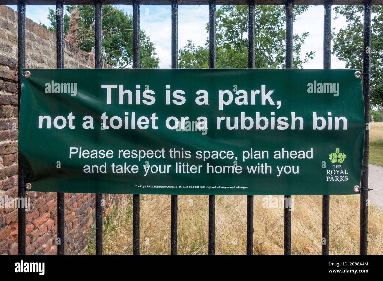 'This is a park, not a toilet or a rubbish bin' sign (see notes for info) on a gated entrance to Bushy Park, Richmond upon Thames, UK. Stock Photo