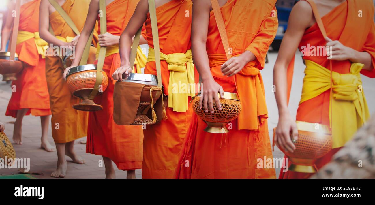 Close of Buddhist novice monks carrying their alms bowls for going on alms round in early morning. Luang Prabang, Laos. UNESCO world heritage town. Stock Photo