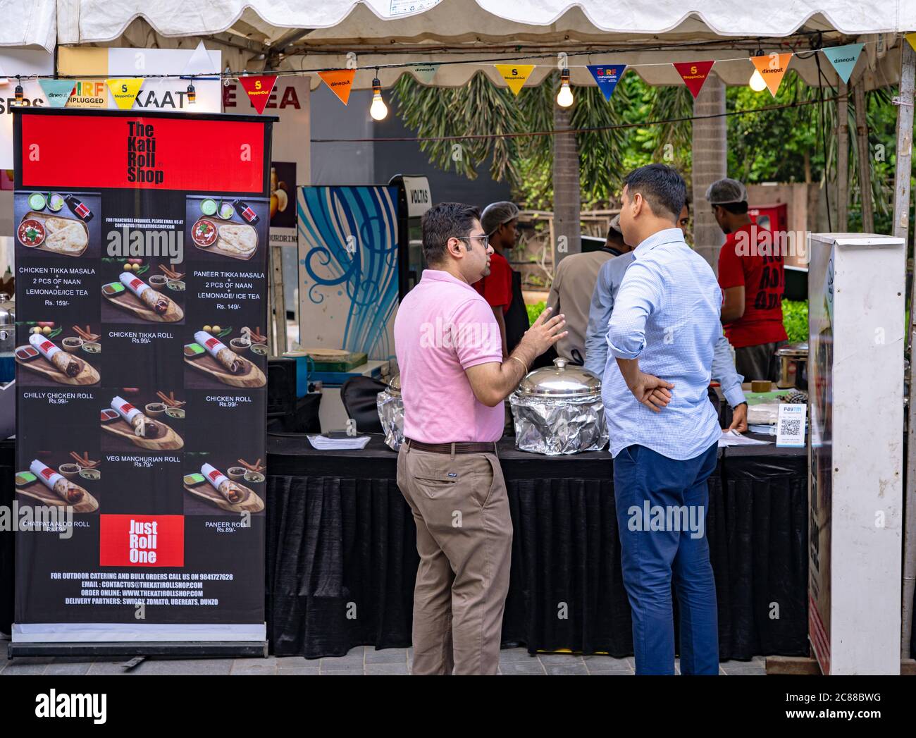 Two customers standing in front of a food stall and deciding their order at a food festival Stock Photo