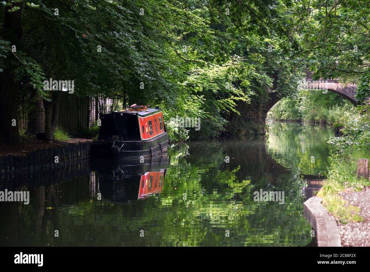 A red boat and an arch bridge reflected in the still waters of the