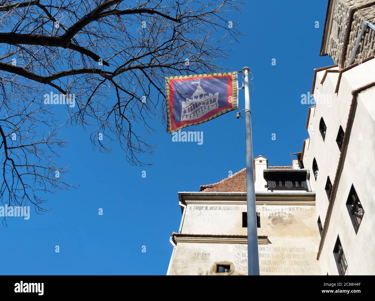 Bran castle flag in front of main entrance against blue sky background. Stock Photo