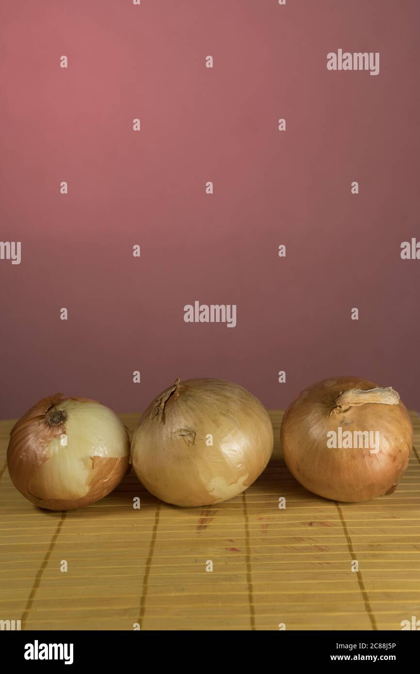 Three onions on board cutting, red background Stock Photo