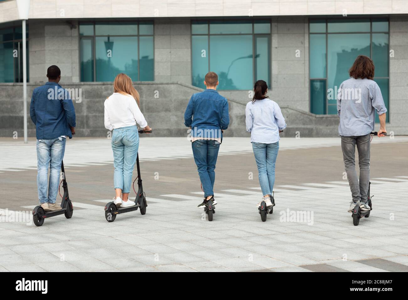 Five students having ride on motorized kick escooters Stock Photo Alamy