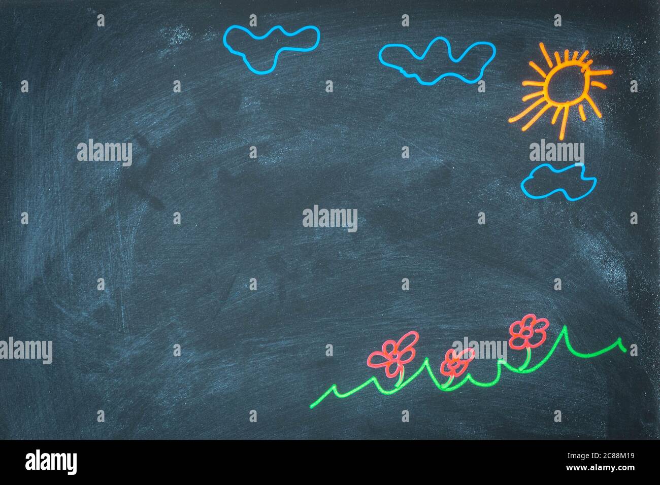 Colored chalk drawing on blackboard for back to school concept. Top view of chalkboard with sun, clouds, flowers, ar grass drawing. Hand drawn picture Stock Photo