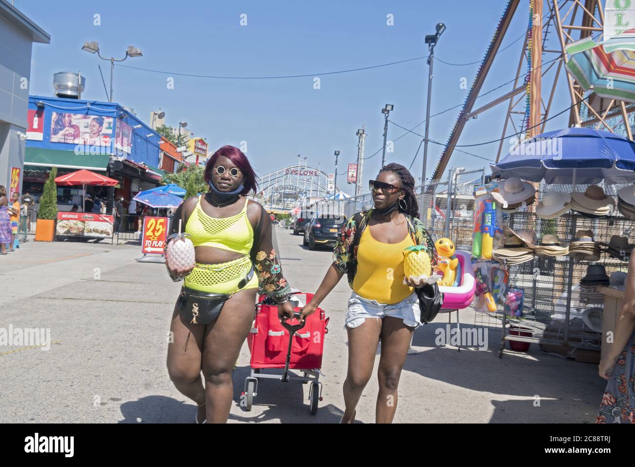 African American friends with fruit drinks in hand walk to the beach at Coney Island on a warm summer day in Brooklyn, New York. Stock Photo