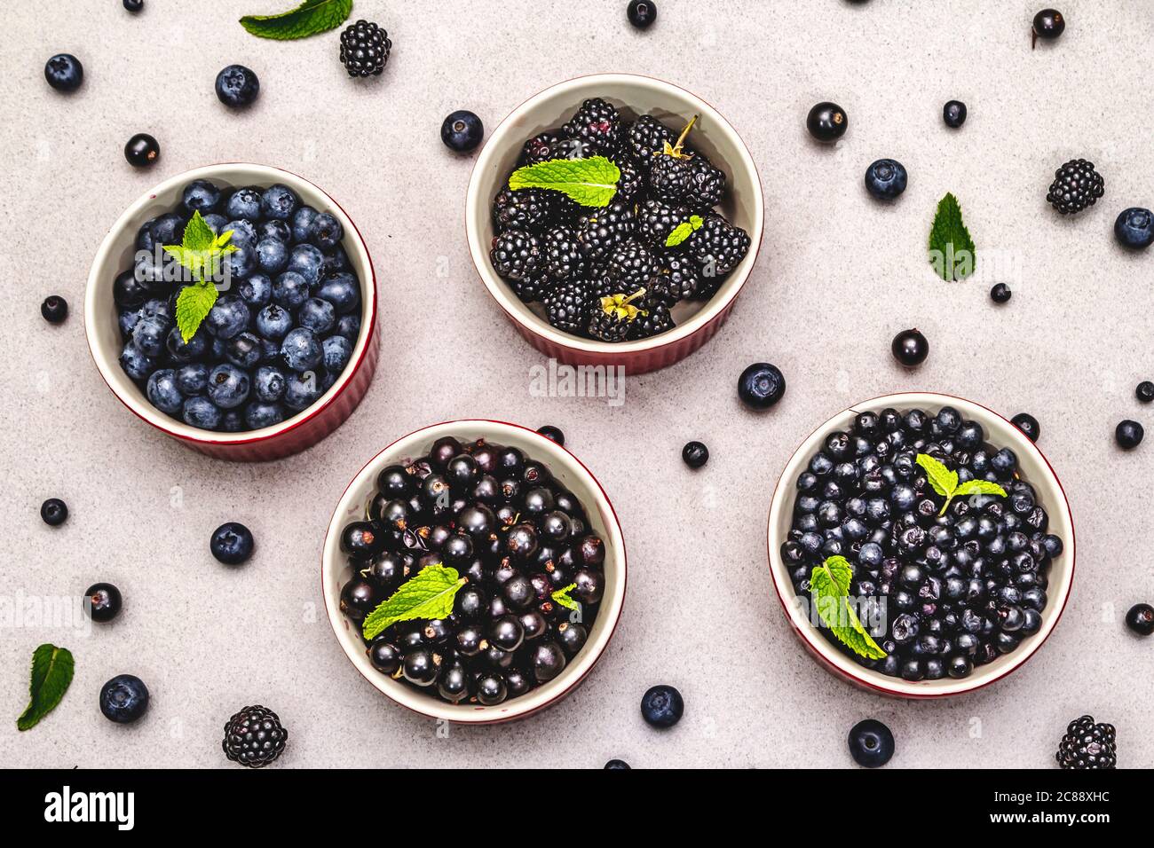 Assorted berries in blue and black colors: bilberry, blueberry, currant and blackberry. Stone concrete background, top view Stock Photo