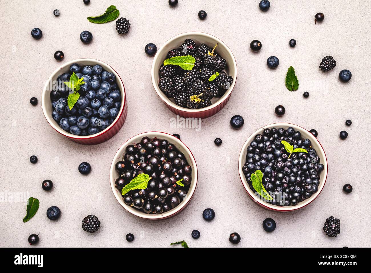 Assorted berries in blue and black colors: bilberry, blueberry, currant and blackberry. Stone concrete background, top view Stock Photo