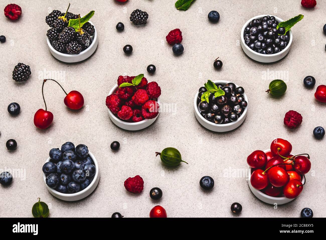 Assorted berries in bowls: bilberry, blueberry, currant, blackberry, cherry and raspberry. Stone concrete background Stock Photo
