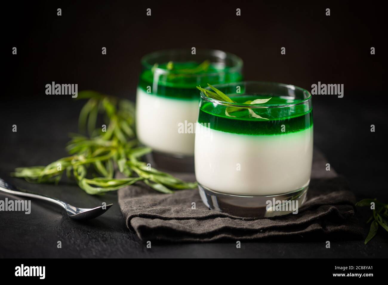 Dessert Panna Cotta with green tarragon sauce and fresh tarragon on dark background Stock Photo