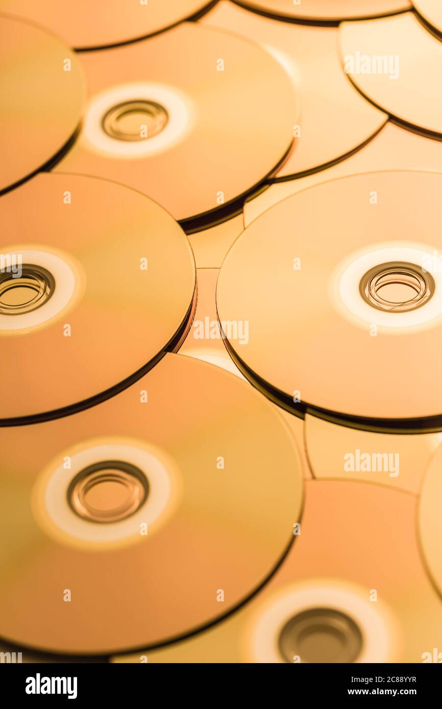 CDs and DVDs in golden tone as background. Soft focus. Stock Photo