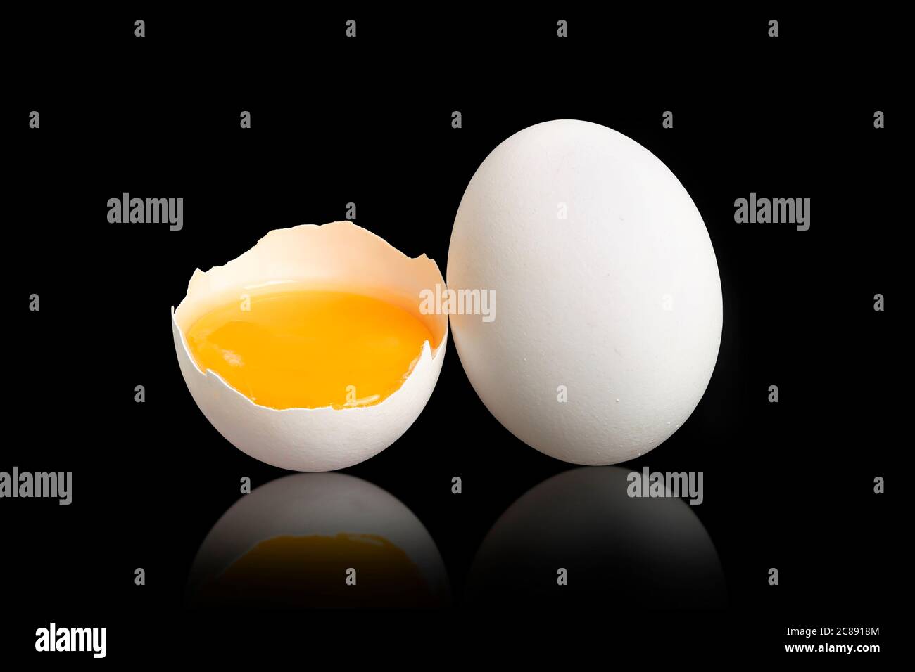 half an egg with yolk next to whole egg on black Stock Photo Alamy