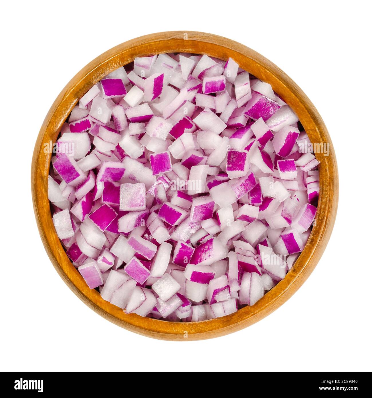 Diced red onions in wooden bowl. Cut cubes of onion cultivar Allium cepa, with purplish red skin and white flesh tinged with red. Closeup, from above. Stock Photo