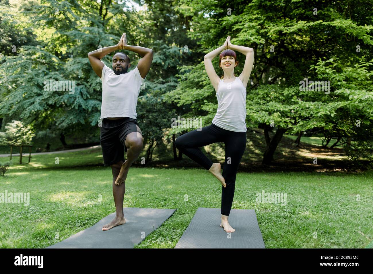 Couple doing yoga in nature. Full length view of young multiethnical