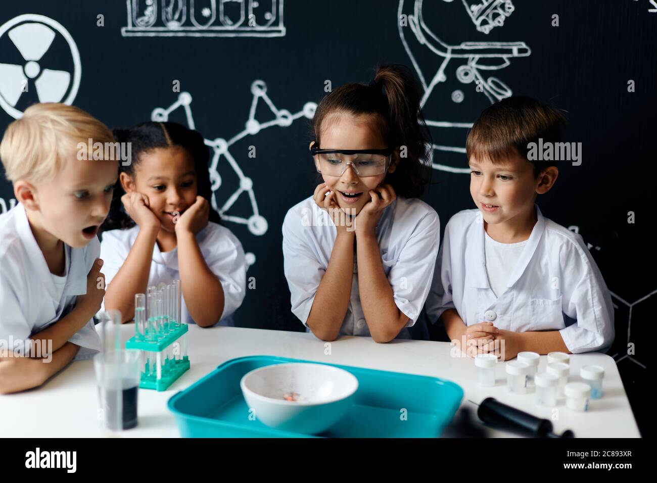 schoolgirl in white coat making experiment with reagents in chemical lab, science student