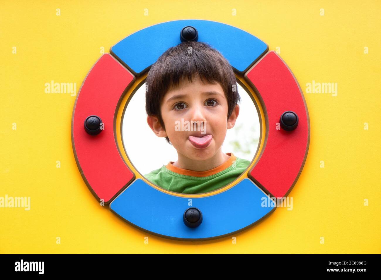 Kid doing a funny expression while looking through a hole Stock Photo