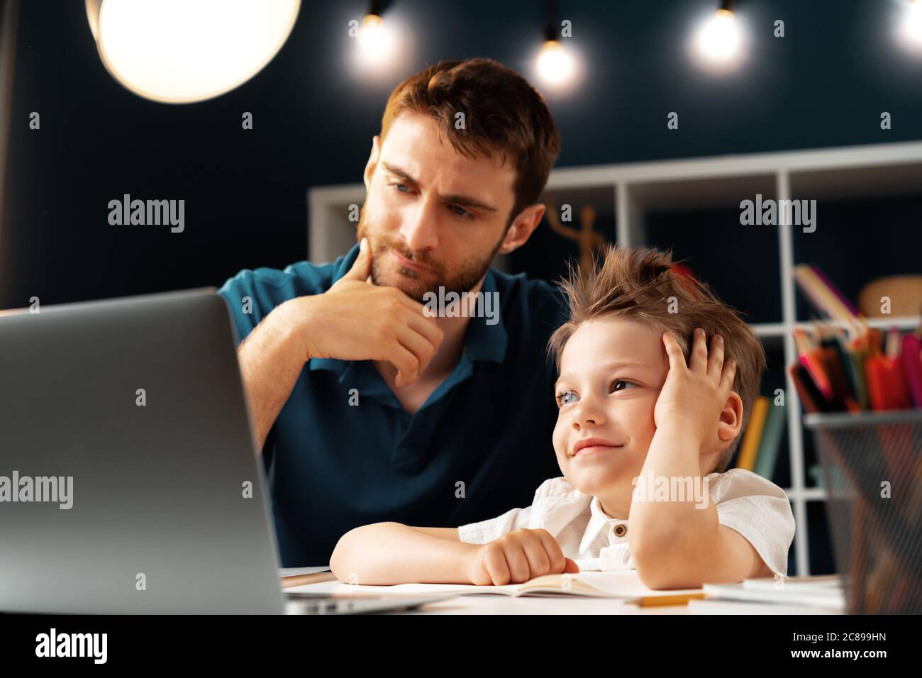 Young boy sitting with his father at the table and using laptop Stock ...