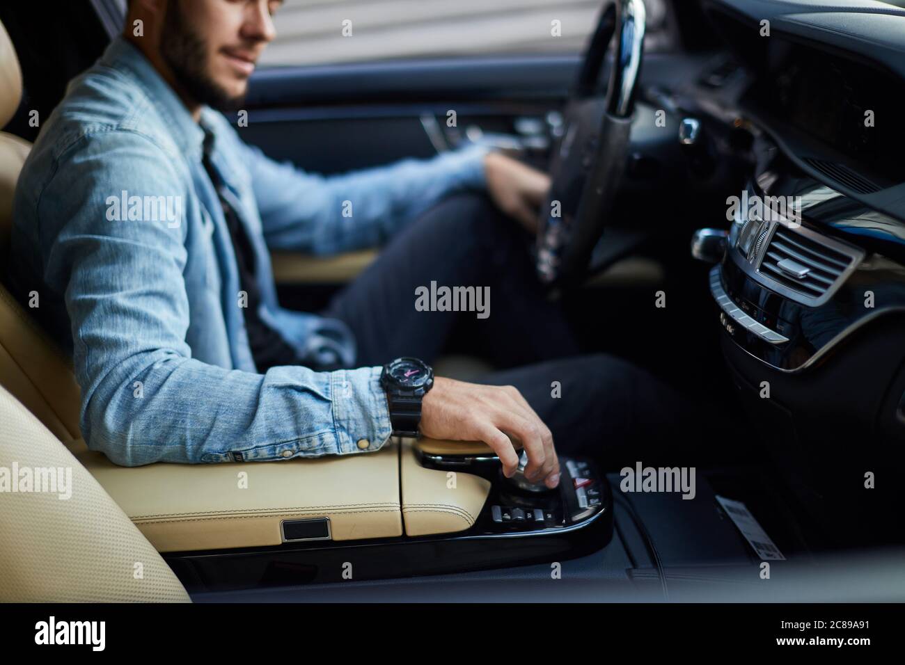 awesome man in denim jacket opening the window of the car. side view cropped photo. control the air condition Stock Photo
