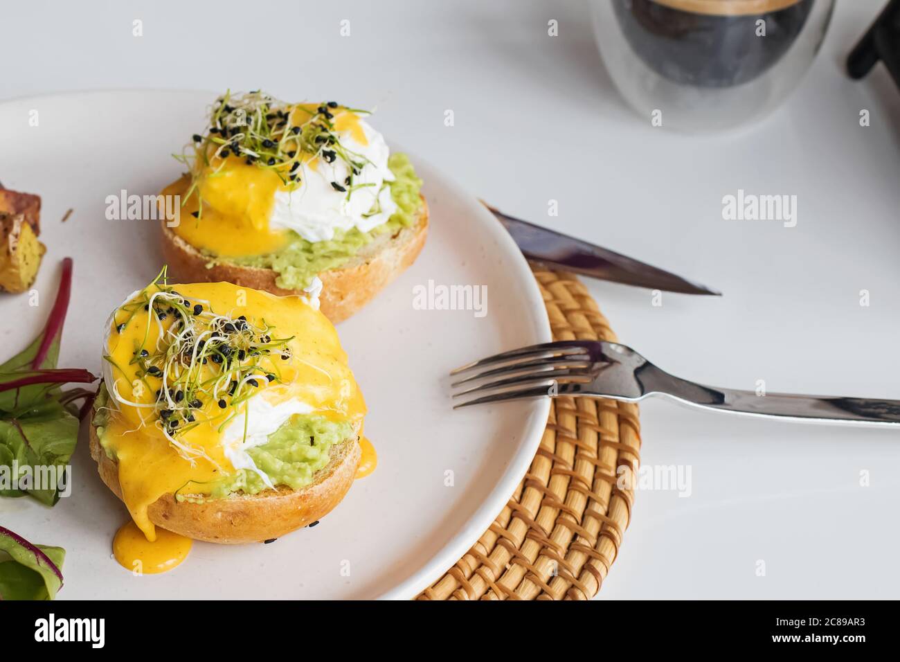 Poached eggs over the bread bun with mashed avocado. Stock Photo