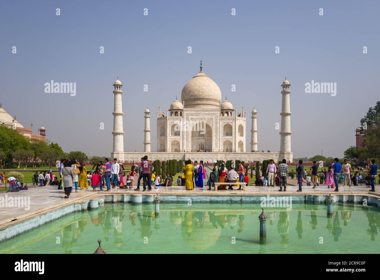 Symmetrical photograph of Taj Mahal on sunny April day, featuring visitors  in  colourful clothes Stock Photo