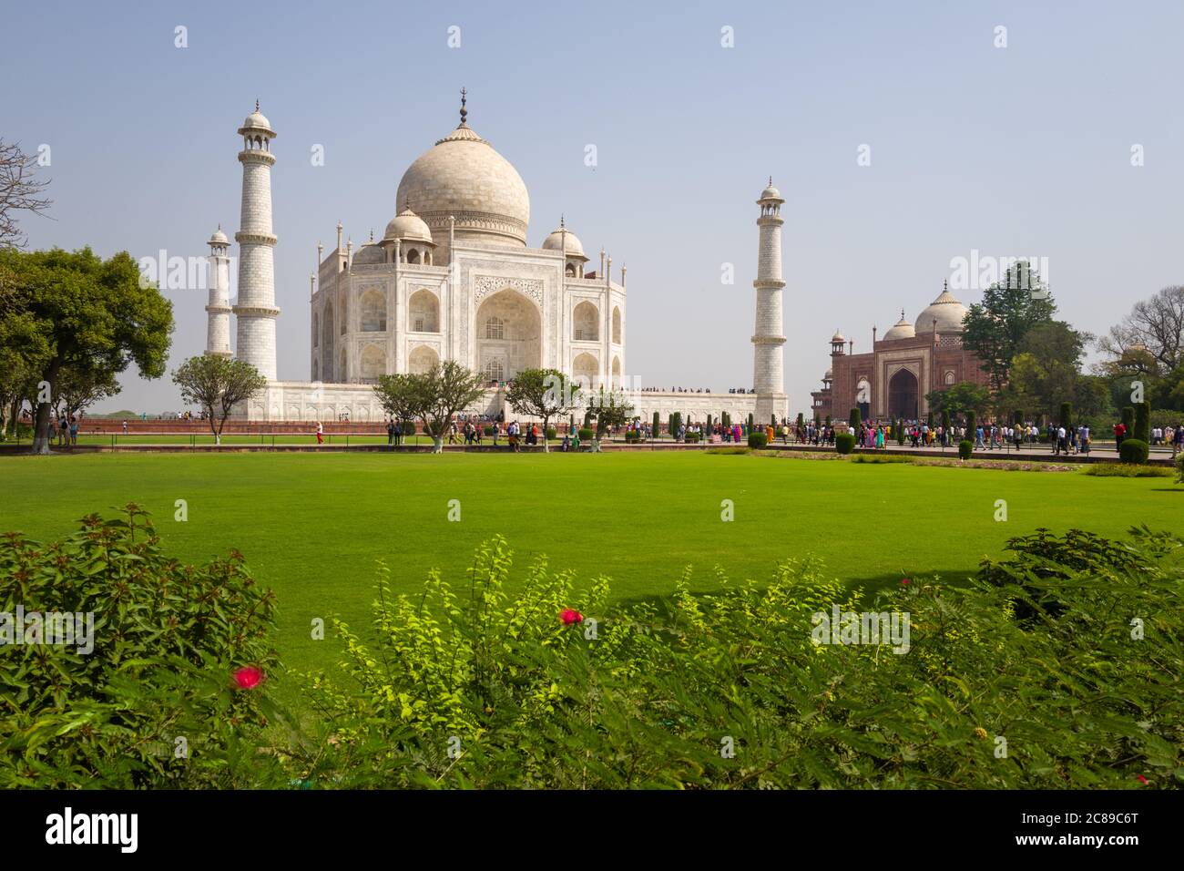 Taj Mahal and outlying sandstone building on sunny April day - shot taken from left showing plants in foreground Stock Photo