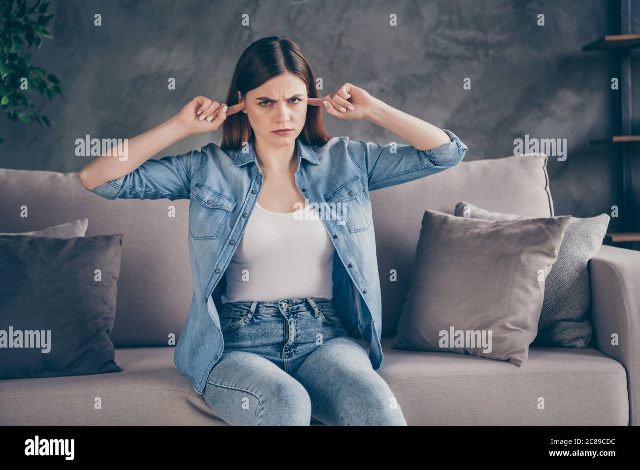 Portrait of irritated angry girl sit divan hate listen all day long