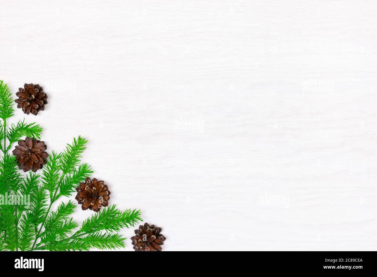 Green Christmas tree branches with pine cones on white wooden table ...
