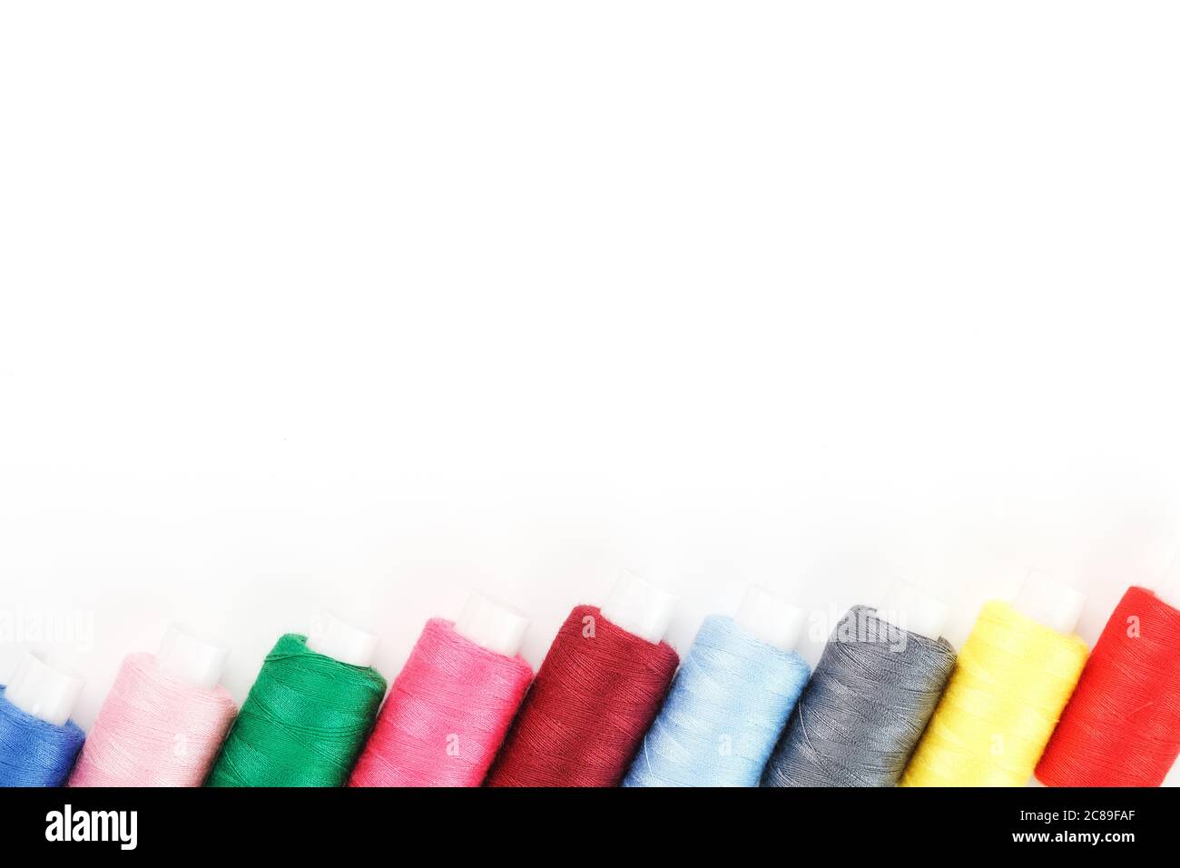 Sewing threads of different colors on reels on a white background. Free ...