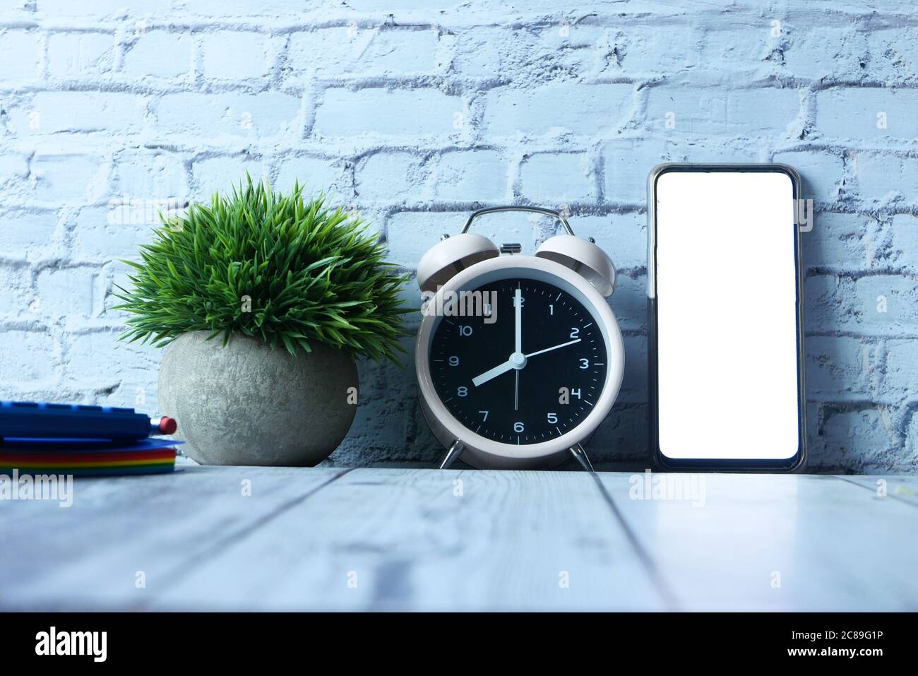 alarm clock, notepad and smart phone with empty screen on table  Stock Photo