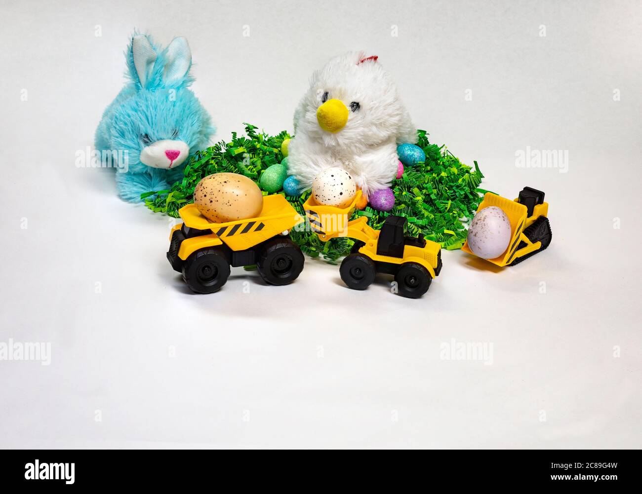 Easter themed photo of stuffed bunny and hen with decorated Easter eggs and a child's toy construction vehicles. Stock Photo