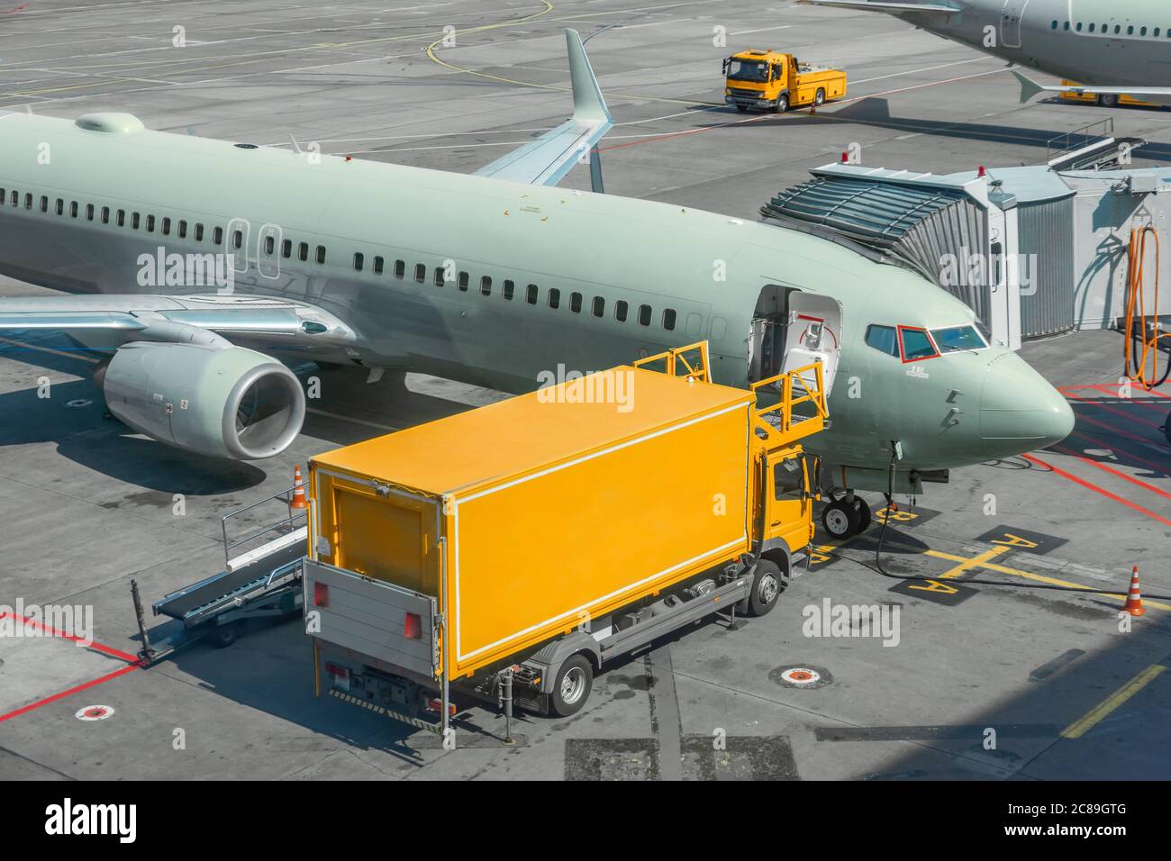 Yellow truck next to a passenger plane, pre-flight service airport Stock Photo