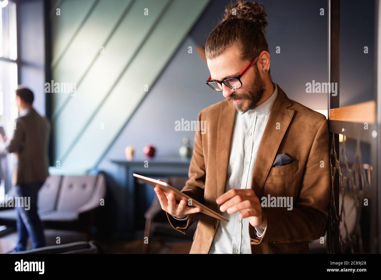 Young handsome businessman holding tablet working, relaxing Stock Photo