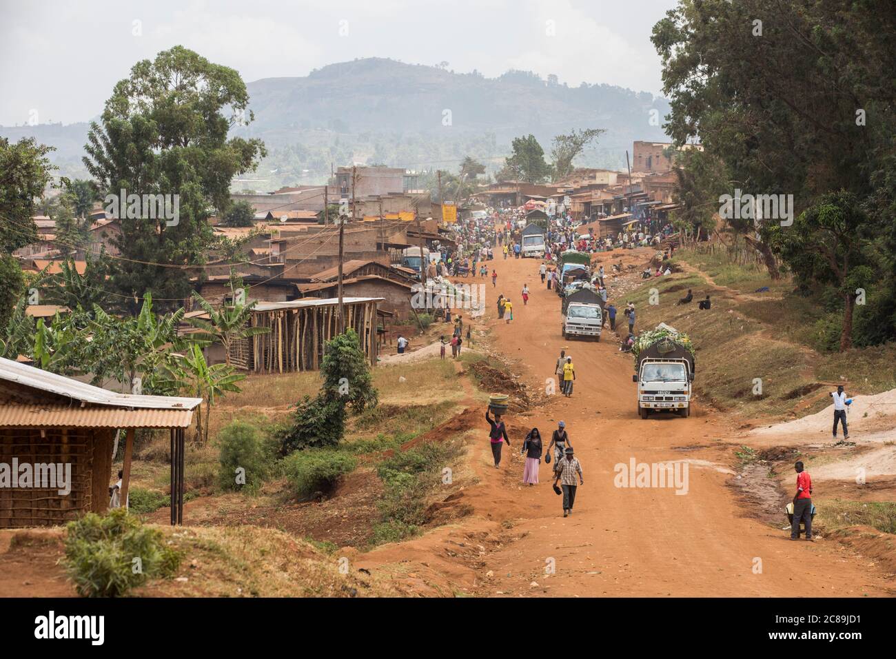A dusty rural road leads to a busy mountain village on the foothills of Mount Elgon, in Eastern Uganda. Stock Photo