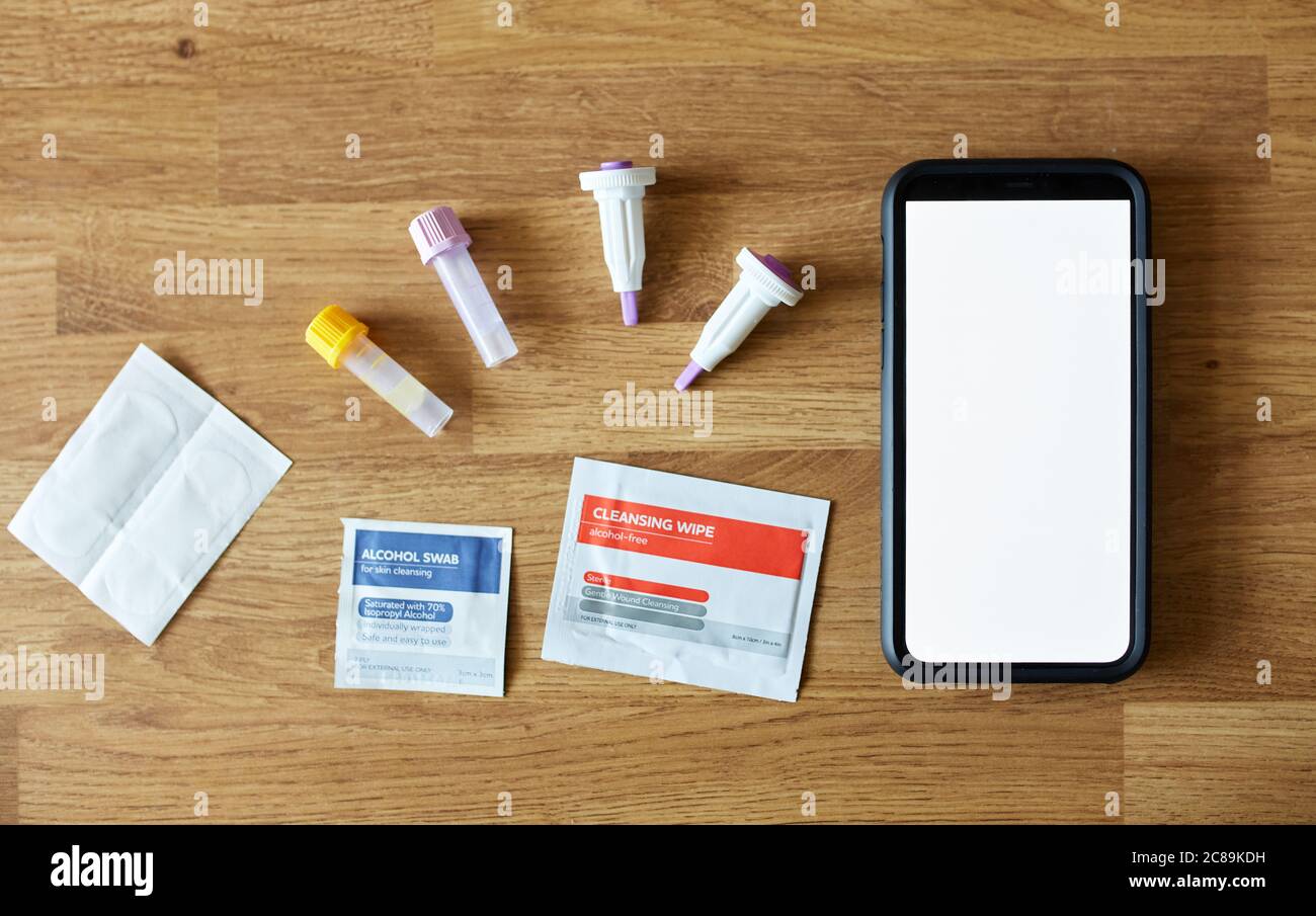Home blood test kit with blank phone screen on wooden table. Stock Photo